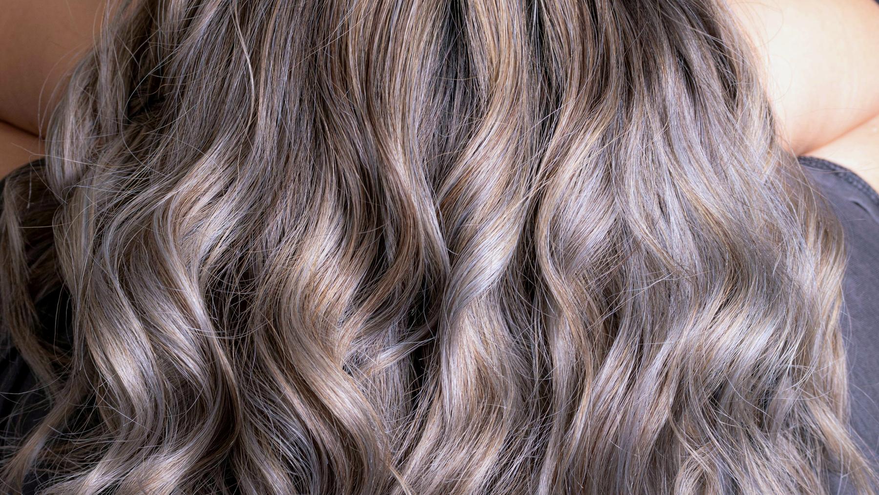 Lived-in balayage, dark at the root and warming through the mid lengths, lit hard from one side.
