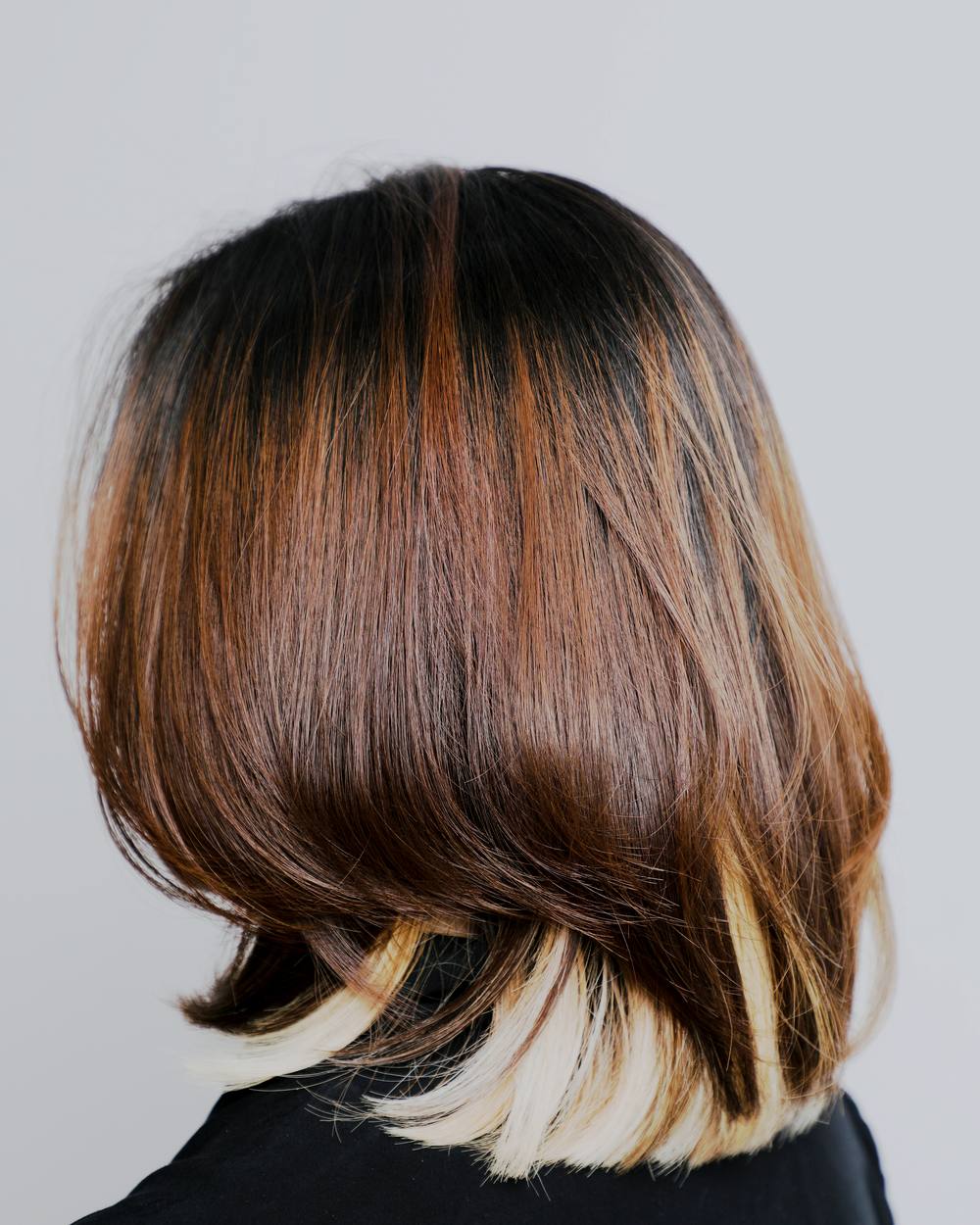 A blunt bob cut to the jaw, dark and glass smooth, with one unbroken band of shine across it.